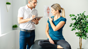 woman holding shoulder talking to physiotherapist