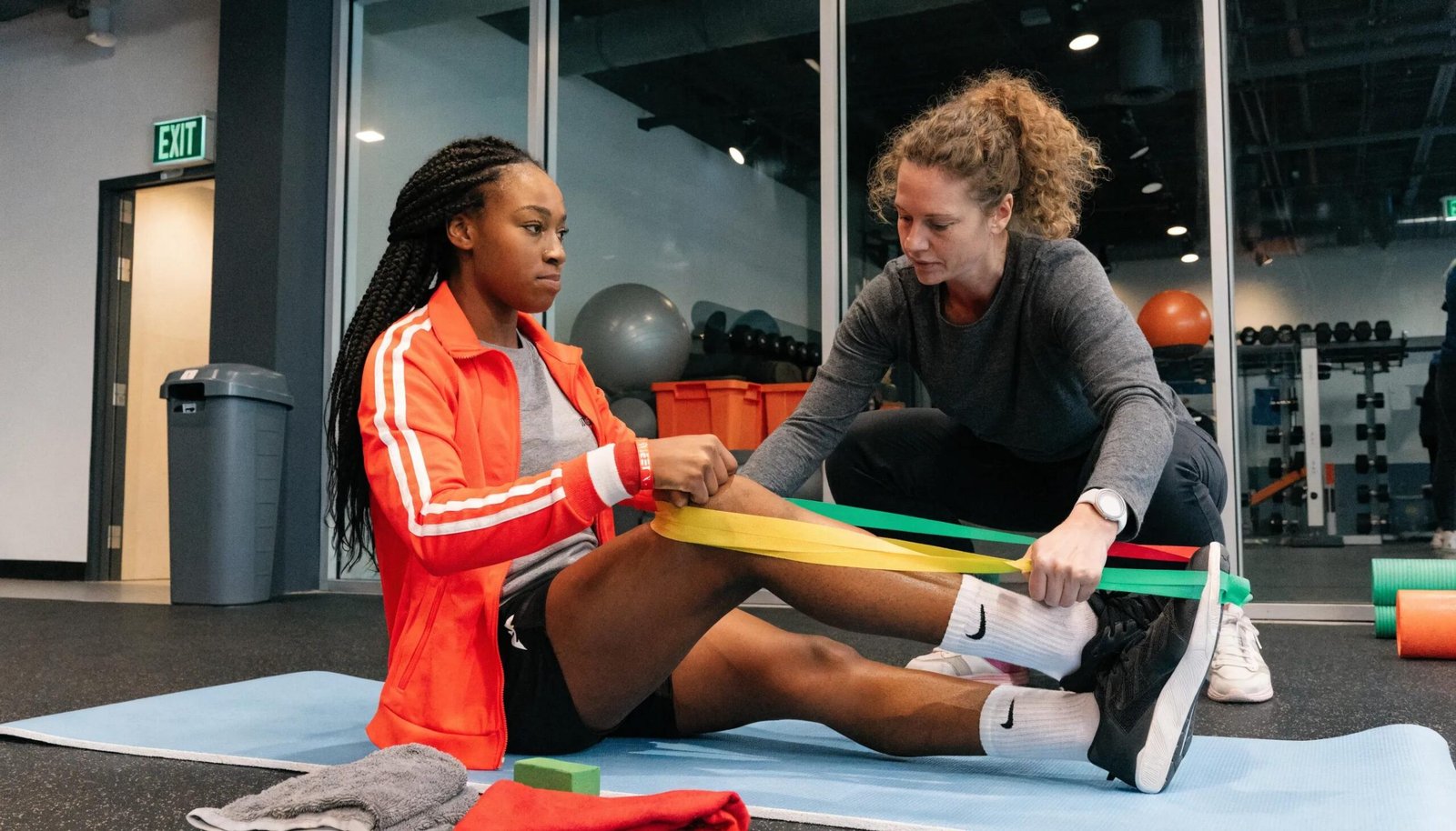 Athlete receiving physiotherapy for sports injury with guidance from therapist